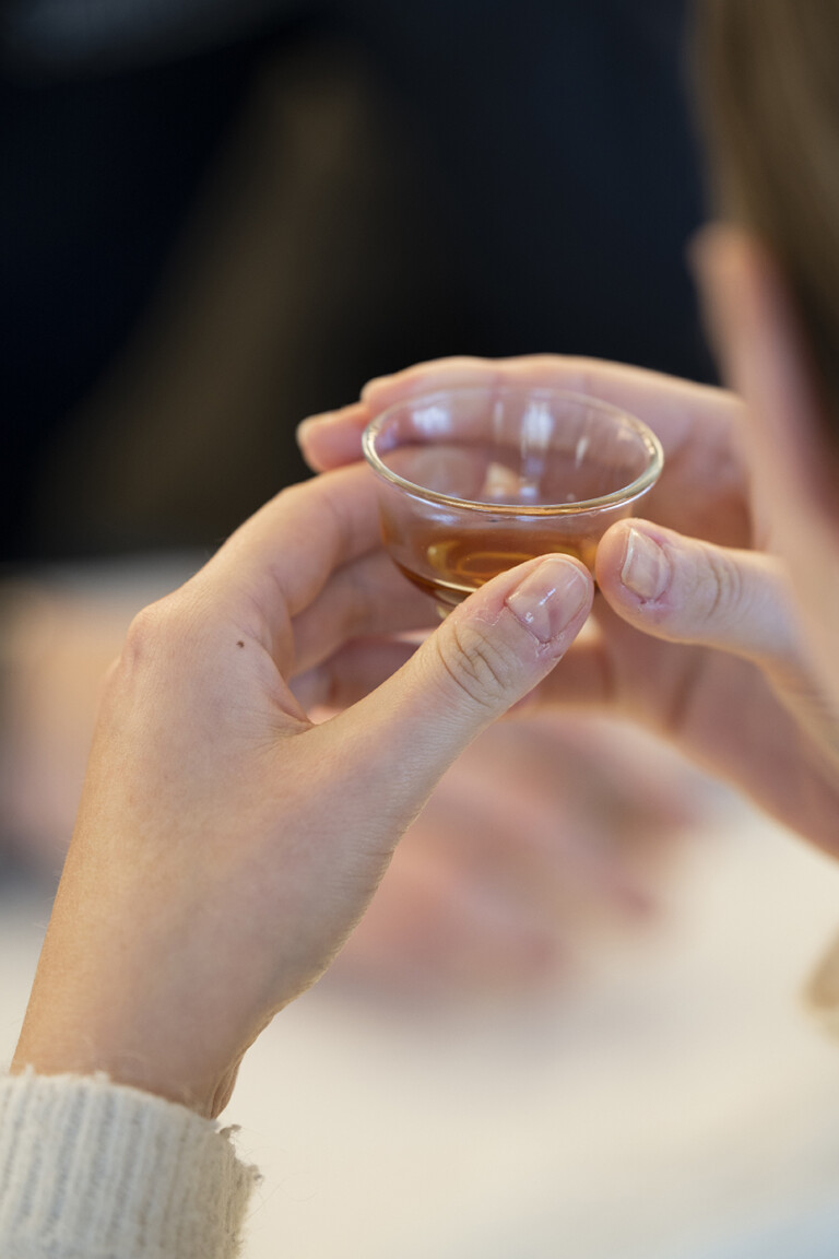Mains tenant une petite tasse de thé ambrée